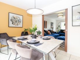 A dining room with a table and chairs overlooking a living room at Manor Park View in Norwich