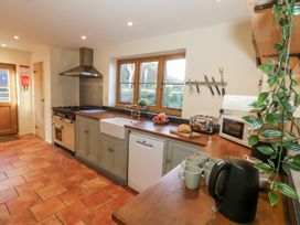 A kitchen with a stove, sink, and various appliances at Honeysuckle Cottage in Smallridge Nr. Axminster