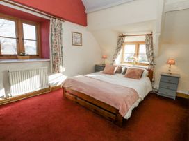 A bedroom with a bed and two windows at Honeysuckle Cottage Smallridge Nr. Axminster