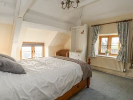 A bedroom with a bed and windows at Honeysuckle Cottage Smallridge Nr. Axminster