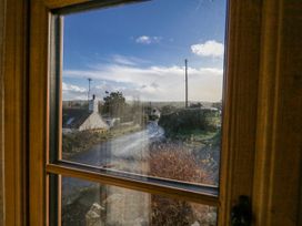 A view of houses and a road through a window at Honeysuckle Cottage in Smallridge Nr. Axminster