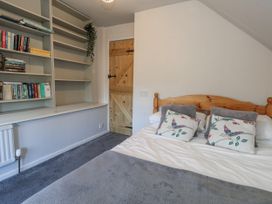 A bedroom with a bed and bookshelf at Honeysuckle Cottage in Smallridge Nr. Axminster