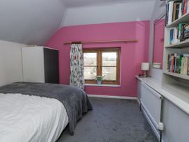 A bedroom with a bed and shelf filled with books at Honeysuckle Cottage in Smallridge Nr. Axminster