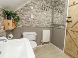 A bathroom with a sink, toilet, mirror, and hooks at Honeysuckle Cottage Smallridge Nr. Axminster