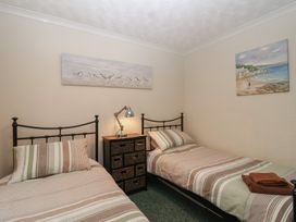 A bedroom with two beds and paintings on the wall at Willow Lodge near Liskeard