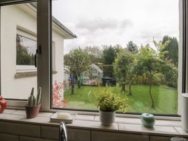 A view of a garden with a greenhouse from a kitchen window at Apple Byrd in Kendal