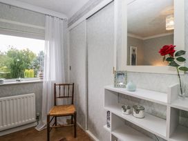 A room with a chair, shelf, and mirror at Apple Byrd in Kendal