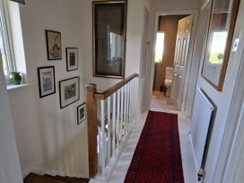 A hallway with a staircase and pictures on the wall at Apple Byrd in Kendal