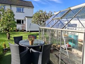 A table and chairs with a greenhouse in the garden at Apple Byrd in Kendal