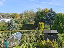A garden with a greenhouse and shed at Apple Byrd in Kendal