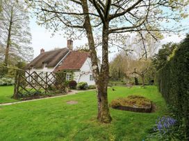 A garden with a house and trees at Plush Cottage in Plush