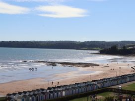 A beach scene with beach huts and people walking on the sand at Beachside