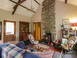 A living room with a stone fireplace and wooden furniture at Tyn Y Fron in Brynherbert near Llanrhystud