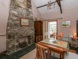 A dining room with a stone fireplace and wooden table at Tyn Y Fron Brynherbert near Llanrhystud