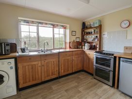A kitchen with wooden cupboards and appliances at Tyn Y Fron in Brynherbert near Llanrhystud