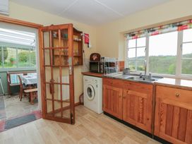 A kitchen with a washing machine and sink at Tyn Y Fron in Brynherbert near Llanrhystud