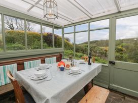 A conservatory with a table set for dining at Tyn Y Fron Brynherbert near Llanrhystud