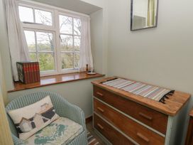 A room with a window, a chest of drawers, and a chair at Tyn Y Fron in Brynherbert near Llanrhystud