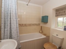 A bathroom with a bathtub, toilet, and window at Tyn Y Fron Brynherbert near Llanrhystud