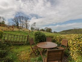 A garden with a wooden table and chairs at Tyn Y Fron Brynherbert near Llanrhystud