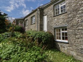 An outdoor view of a stone cottage surrounded by greenery at Tyn Y Fron in Brynherbert near Llanrhystud