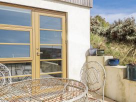 An outdoor seating area with a table and chairs at Teach Tra East in Perranporth