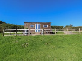 A cabin with a fence and chairs at Sychnant Farm Retreat in Llanedi near Pontarddulais