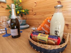 A kitchen counter with a bottle of Asti, milk, snacks, and glassware at Sychnant Farm Retreat Llanedi near Pontarddulais