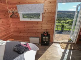 A bedroom with a bed and window overlooking a landscape at Sychnant Farm Retreat Llanedi near Pontarddulais