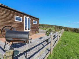 A wooden cabin with a grill and fence at Sychnant Farm Retreat Llanedi near Pontarddulais