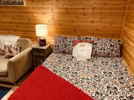 A bedroom with a bed, lamp and sofa at Sychnant Farm Retreat in Llanedi near Pontarddulais
