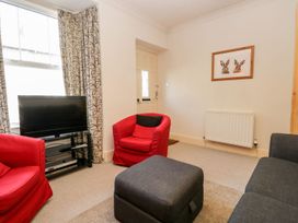 A living room with a television and seating at The Burrow in Windermere