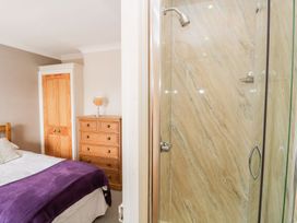 A bedroom with a bed, wardrobe, dresser, and shower at The Burrow in Windermere