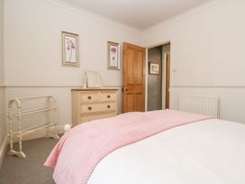A bedroom with a bed, dresser, and door at The Burrow in Windermere