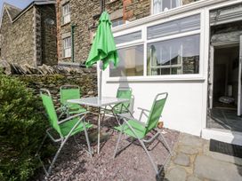 An outdoor space with a table and green chairs at The Burrow in Windermere