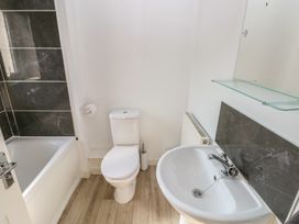 A bathroom with a bathtub, toilet, sink and mirror at Swansea Escape in Swansea