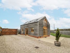 A house with wooden cladding and a gravel driveway at Cedar Barn