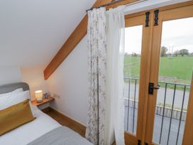 A bedroom with a bed and window overlooking a field at Cedar Barn 