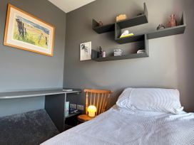 A bedroom with a bed, chair, and shelf at Sea Holly in St Just