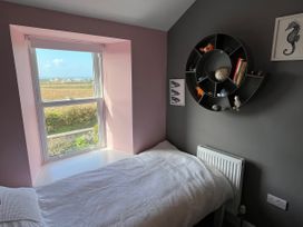 A bedroom with a window, bed, and bookshelf at Sea Holly in St Just