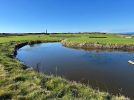 A golf course with a pond and lighthouse at Sea Holly in St Just