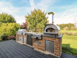 An outdoor kitchen with a grill and pizza oven at Manor Farm House in Merton near Bicester