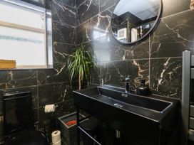 A bathroom with black tiled walls at 61 Lloyd Street West in Llandudno