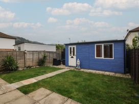 A garden with a blue shed and stone pathway at 61 Lloyd Street West in Llandudno
