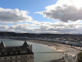 A view of a beach and pier with buildings at 61 Lloyd Street West in Llandudno