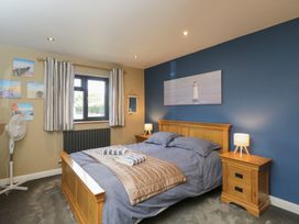 A bedroom with a bed, bedside tables, and artworks at Willow Cottage in Whiteparish