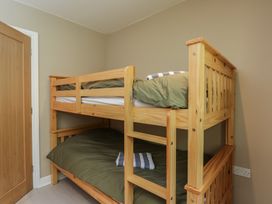 A bedroom with a wooden bunk bed and green bedding at Willow Cottage Whiteparish