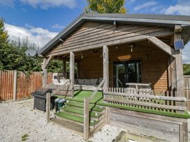 A wooden cabin with outdoor seating area at Willow Cottage in Whiteparish