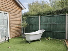 A garden with a bathtub and wooden fence at Willow Cottage in Whiteparish