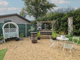 A garden with a table, chairs, barrel and bench at Willow Cottage in Whiteparish